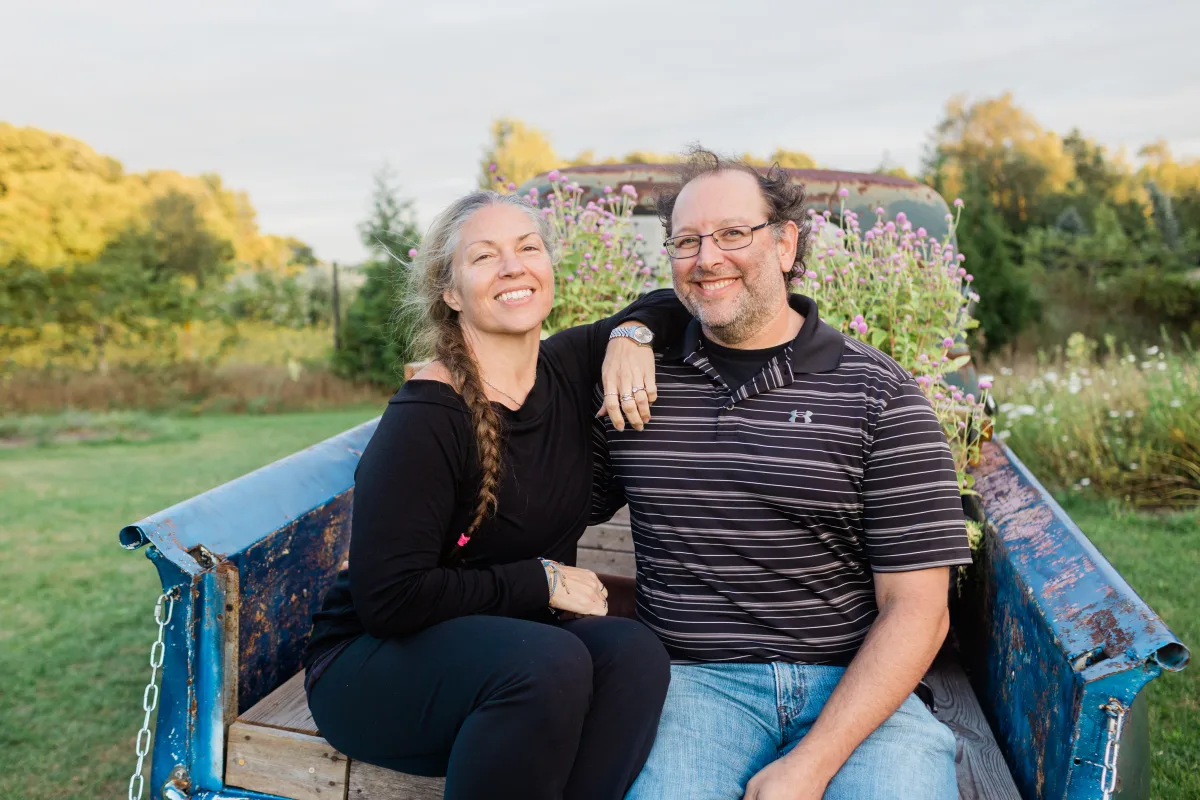 Alicia and Dave smiling together on the back of a blue pickup truck.